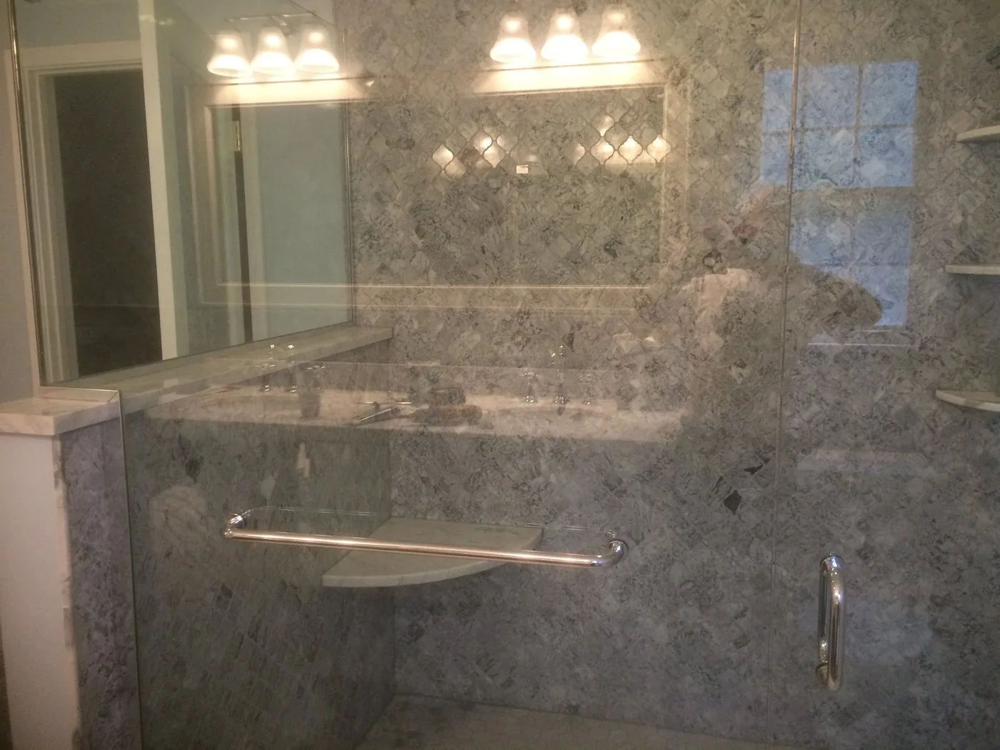 Marble tiled shower and tub surround with a glass panel