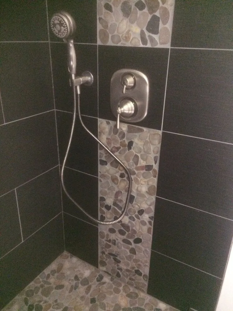 Slate tiled shower with a pebble accent stripe and a rain head