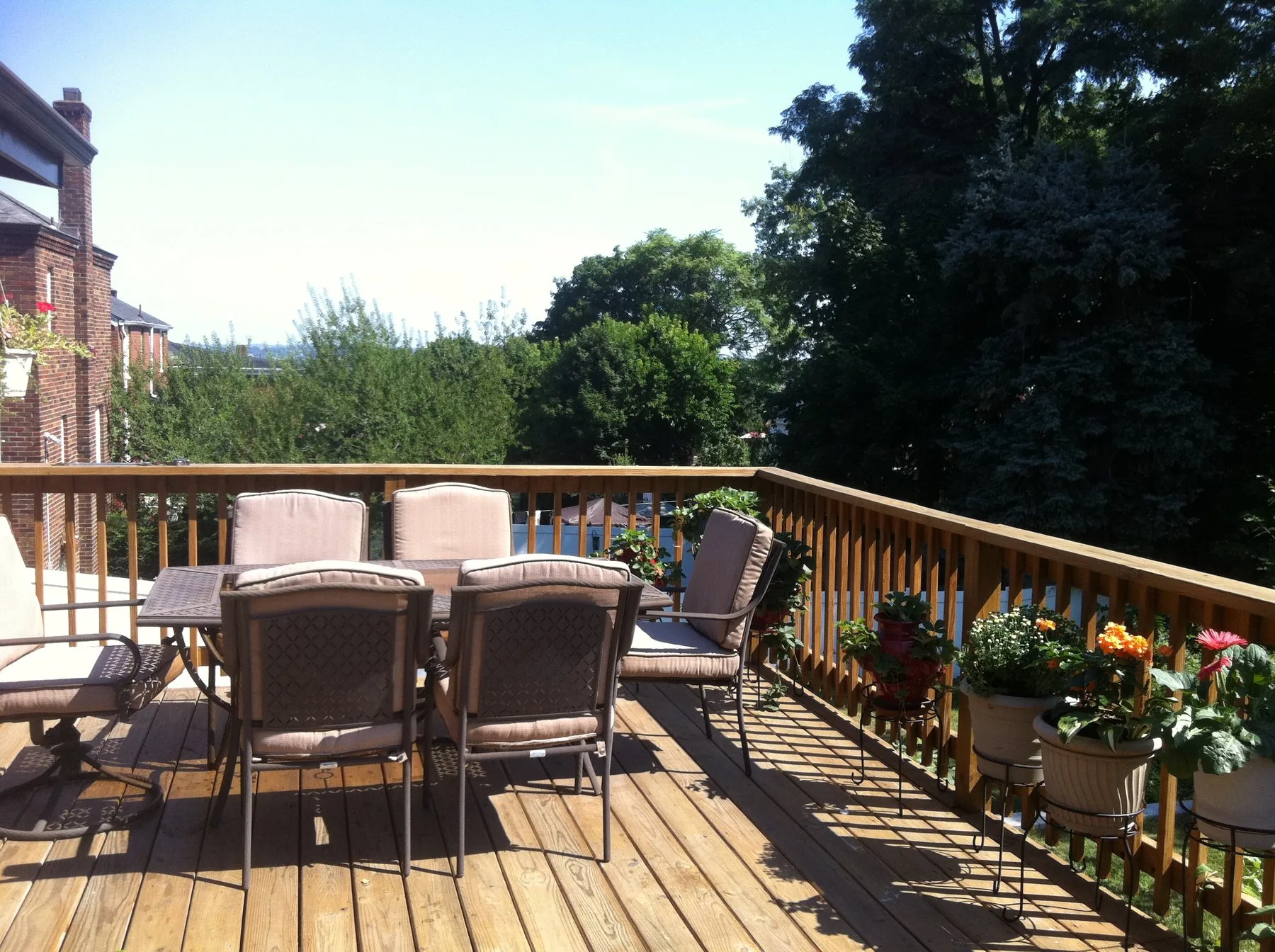 Deck built by Edward Construction with railing, patio furniture, and a view over the trees