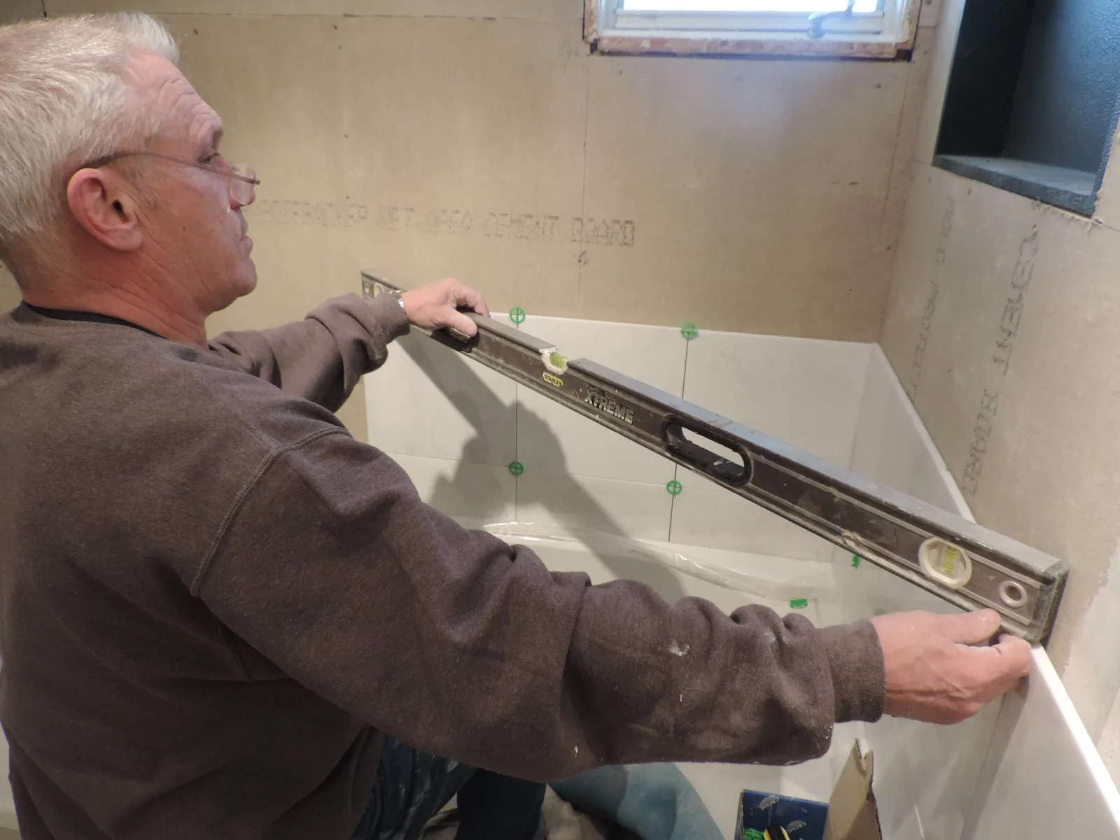Edward of Edward Construction setting a level across a new tub surround
