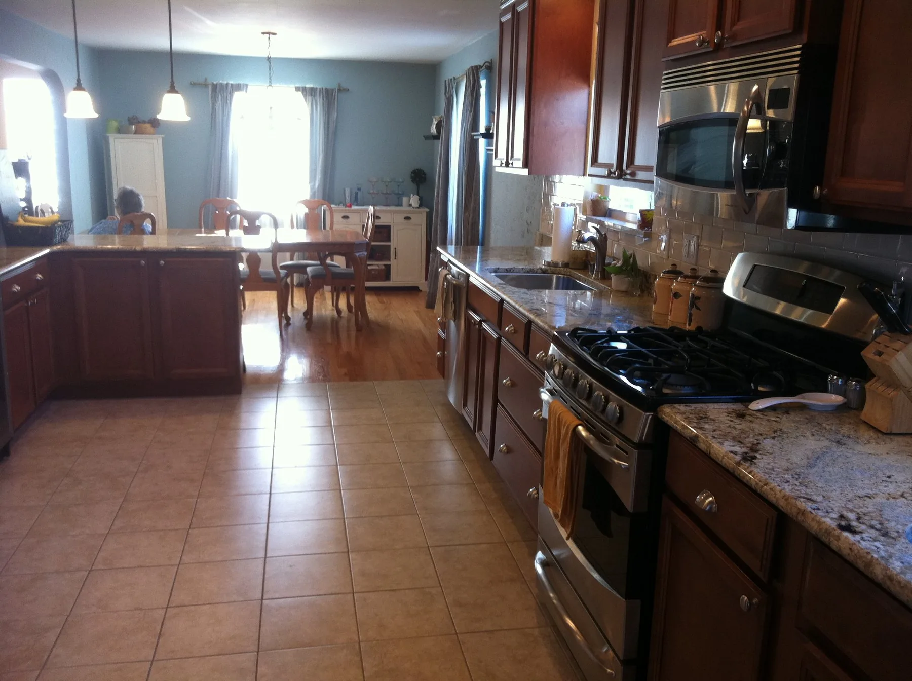 Kitchen remodeled by Edward Construction with cherry cabinets, granite counters, and a tile floor opening onto a dining room
