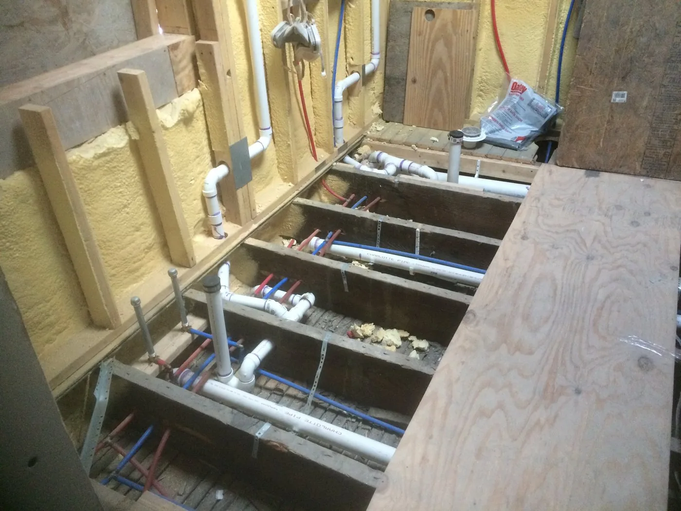 Open floor joists with new supply and drain lines run through them
