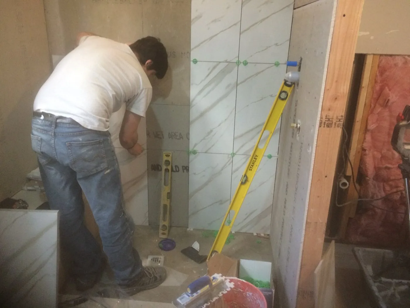 Large format wall tile being set by hand and checked with a level