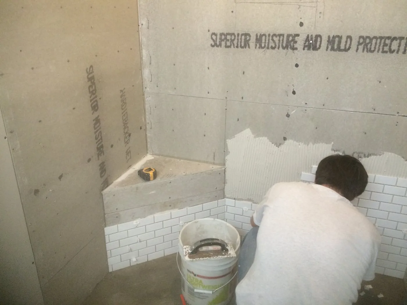 Moisture and mold resistant board installed around a tub with the first courses of subway tile going on